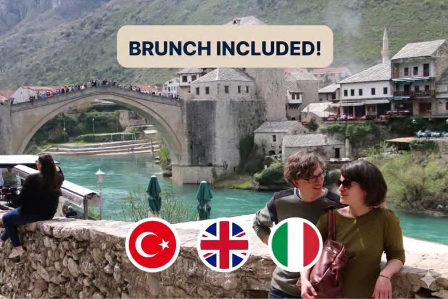 Couple by a stone railing on a riverfront with a historic arched bridge and village, a 'Brunch Included!' banner above, and Turkish, British, and Italian flags nearby.