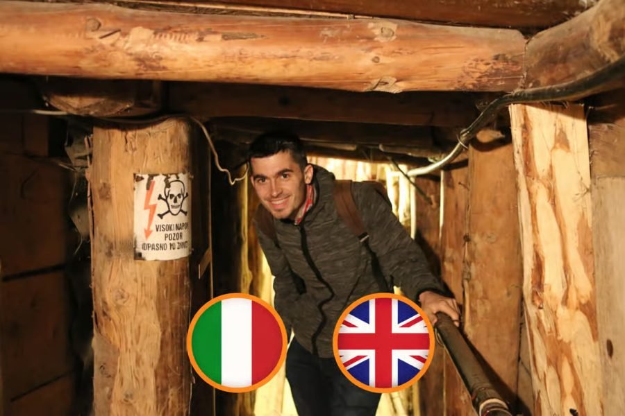 Man with a backpack in a dark wooden mine tunnel, smiling at the camera.